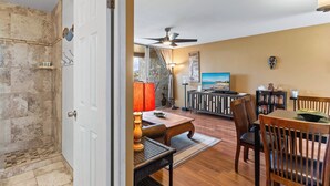 A living room with a dining area, a ceiling fan, a television, and a wall-mounted artwork. - Kalama Terrace P-307 - 3rd-floor Walkup, 7 min Walk to Charley Young Beach, AC! (Kihei)