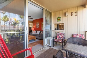 An open sliding glass door leading to a living area with a sofa, a coffee table, and a chair. - Kalama Terrace P-307 - 3rd-floor Walkup, 7 min Walk to Charley Young Beach, AC! (Kihei)