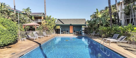 A swimming pool with lounge chairs and a building in the background.
