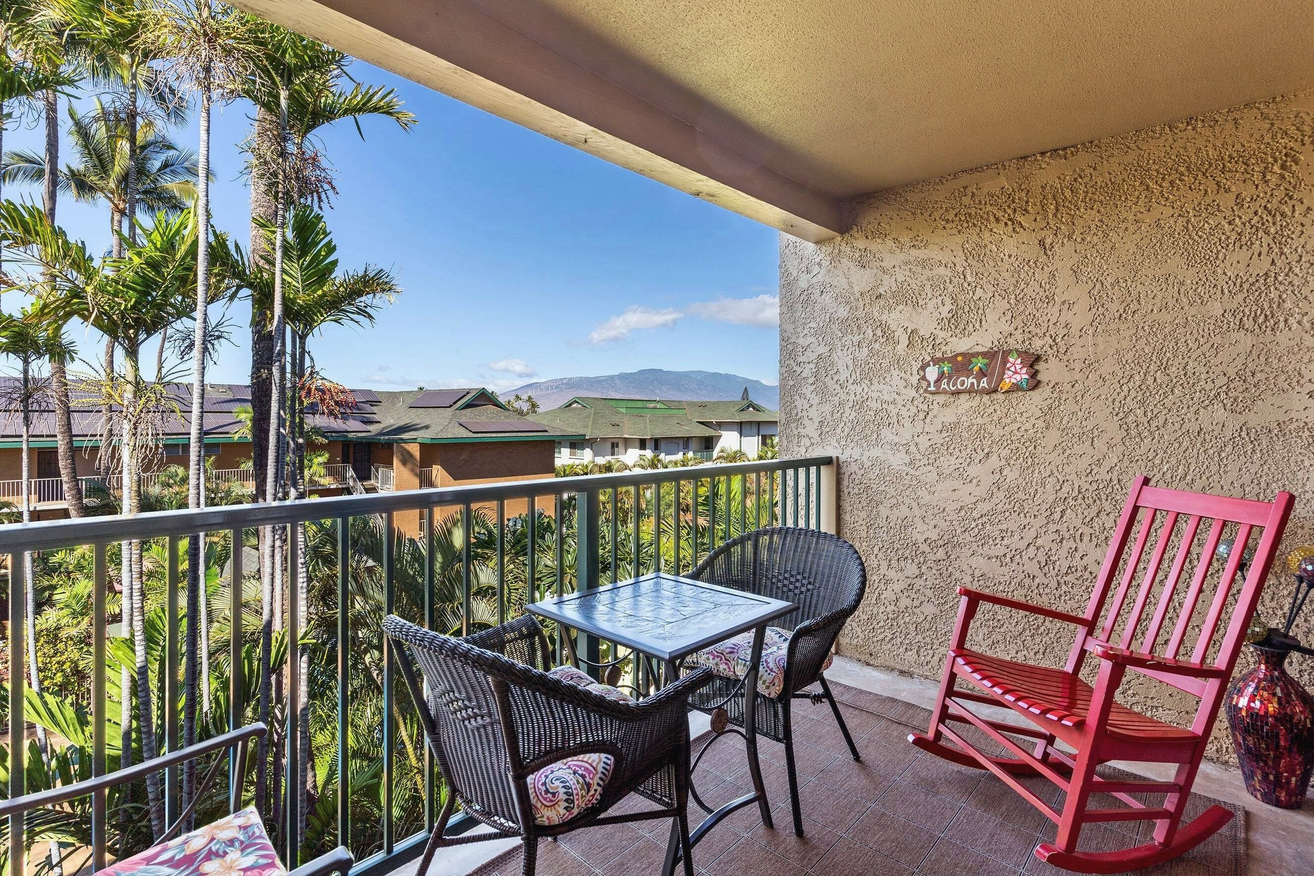 A balcony with a table and chairs, a red rocking chair, and a decorative sign.