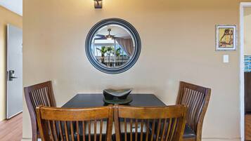 A dining area with a round mirror, two wooden chairs, a table, and a ceiling fan.