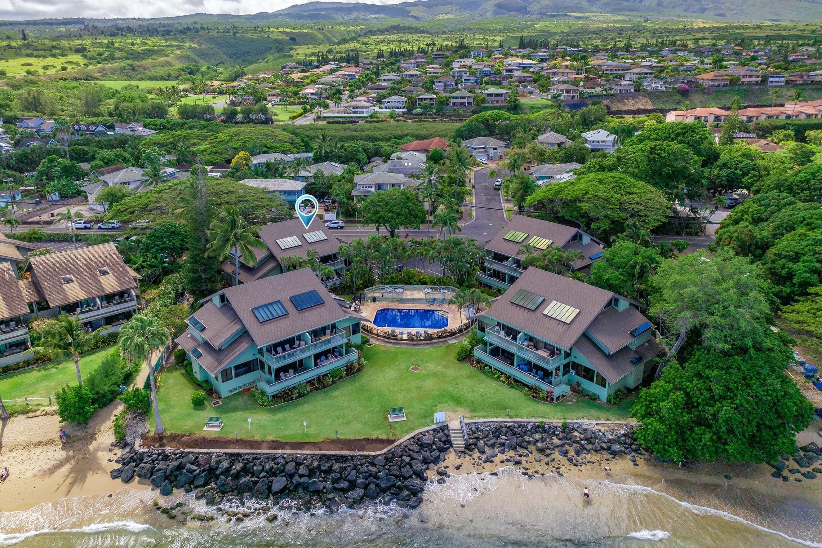 A coastal resort with multiple buildings, a swimming pool, and a rocky shoreline.