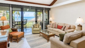 A spacious living area with a glass door leading to a balcony, a ceiling fan, and a view of the ocean. - Kahana Outrigger 4B1 - Breathtaking Ocean Views, Renovated Condo, Secluded Beach (Lahaina)