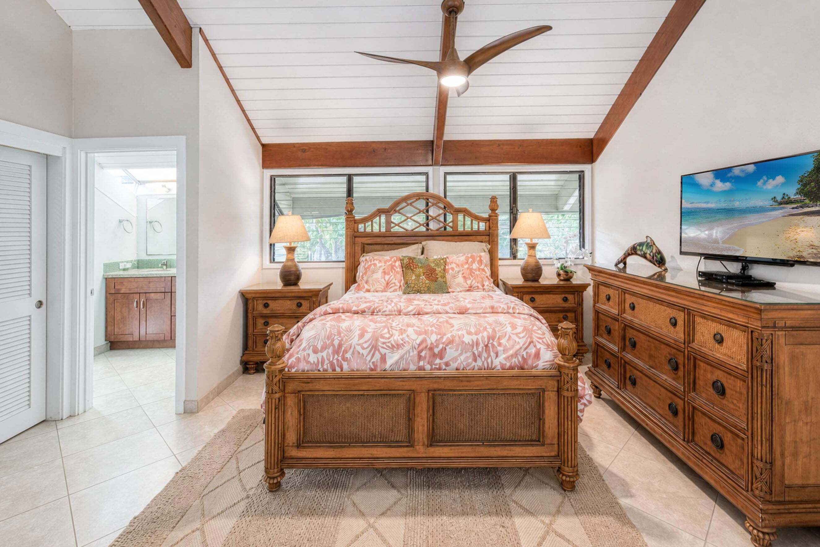 Un dormitorio con cama de madera, mesitas de noche, cómoda y ventilador de techo.