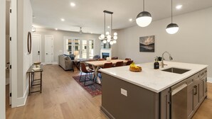 Una cocina moderna con una isla central, electrodomésticos de acero inoxidable e iluminación colgante.