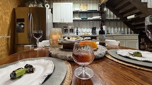 Un coin repas avec une table en bois mise pour le dîner, un verre à vin et une bouteille de vin.