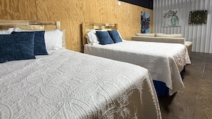 Une chambre d’hôtel avec deux lits, des têtes de lit en bois et un mur blanc agrémenté d’un panneau décoratif.