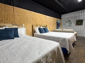 A hotel room with two beds, wooden headboards, and a white wall with a decorative panel.