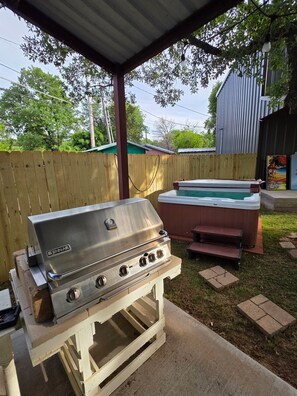 An outdoor grill setup with a hot tub and a covered area.