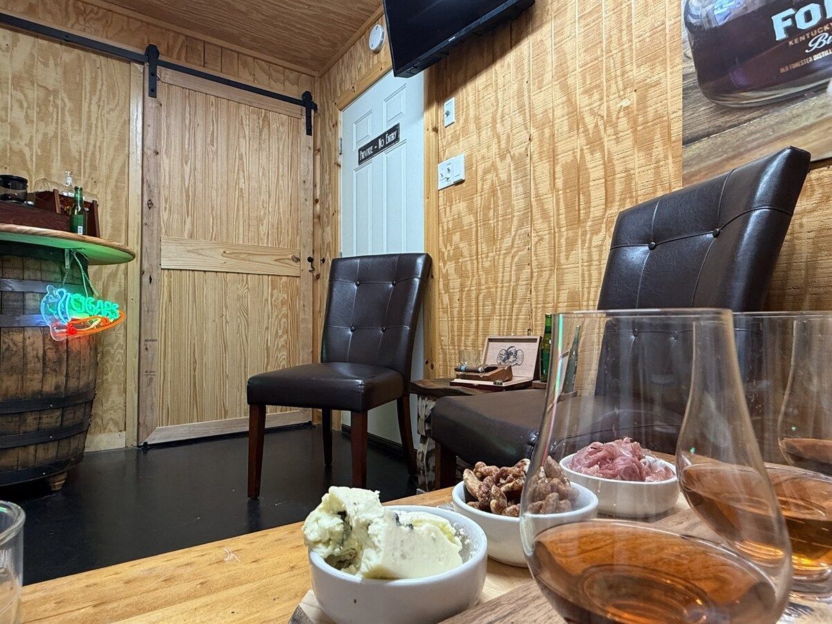 Et interiør i træ med en bar, læderstole og et bord med mad og drikke.
