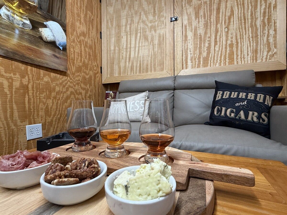 Un salón acogedor con una mesa de madera lista para una comida, un sofá gris con un cojín y un mueble de madera al fondo.