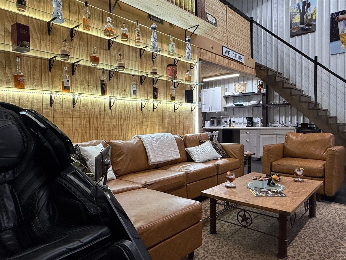 Un interior moderno con un sofá de cuero, una mesa de centro y una pared que exhibe varias botellas.