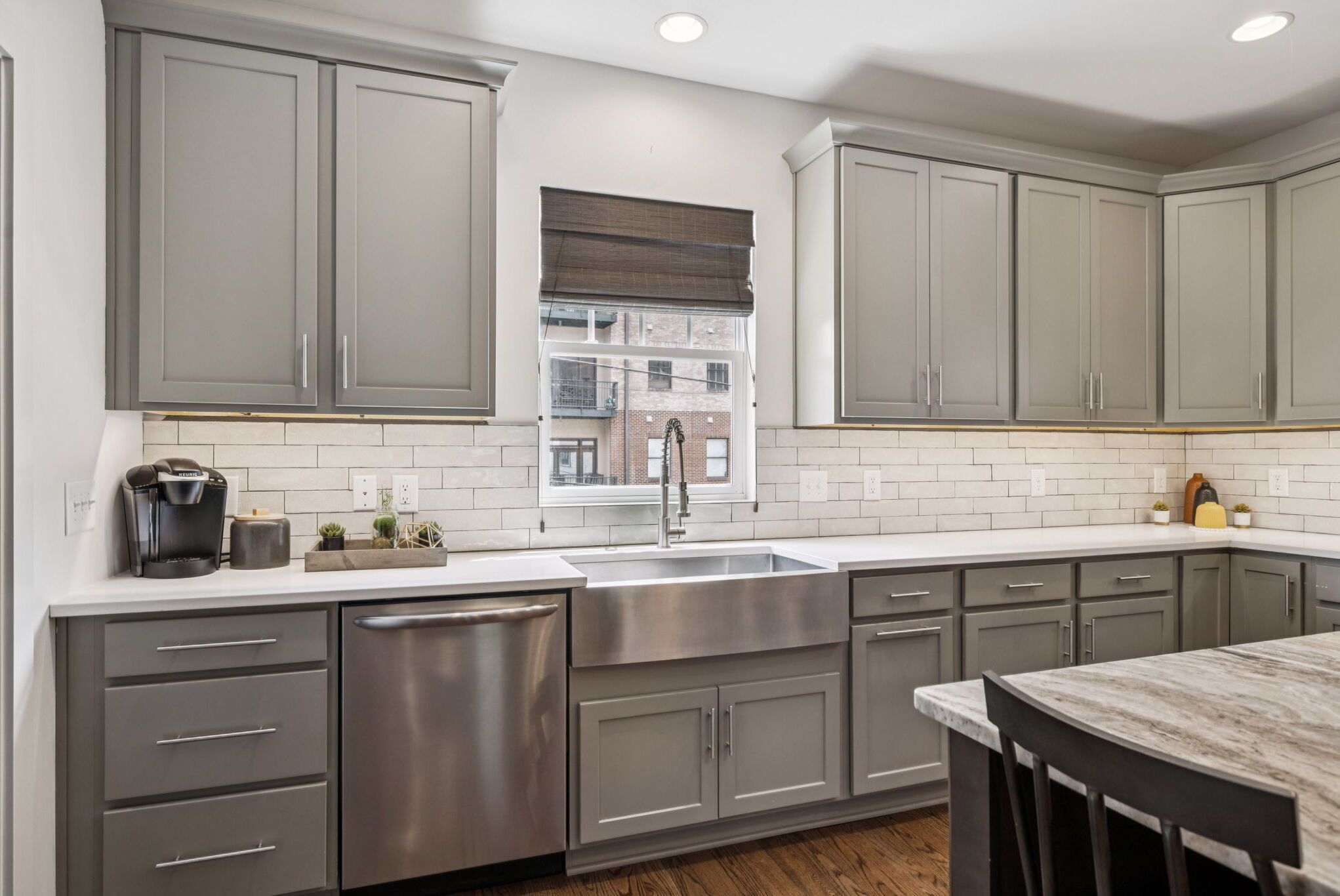 A modern kitchen with grey cabinets, stainless steel appliances, and a white tiled backsplash.