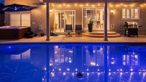 A poolside area with a hot tub, outdoor seating, and string lights.
