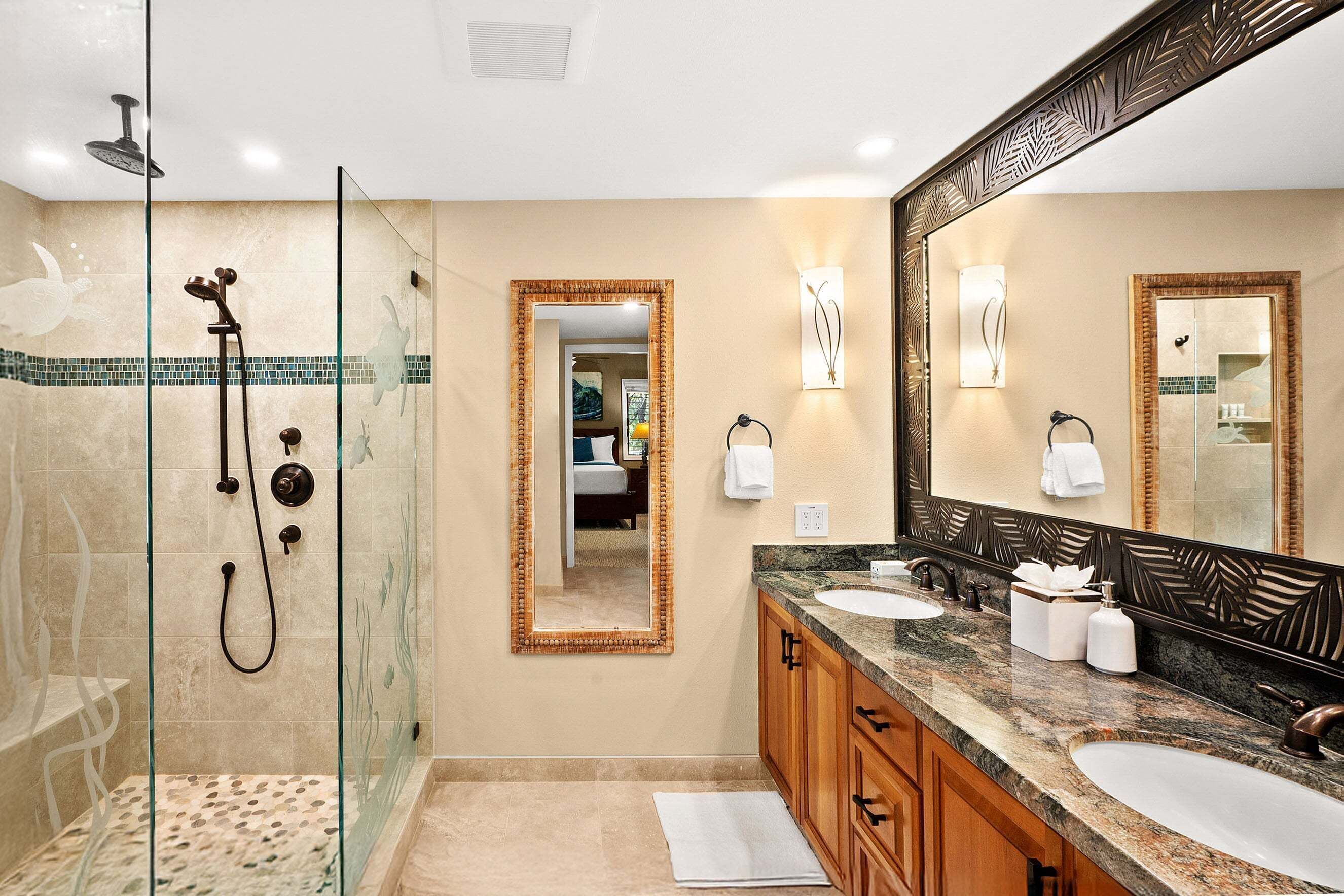 Une salle de bain avec une douche à parois de verre, deux lavabos, un grand miroir et un porte-serviettes.