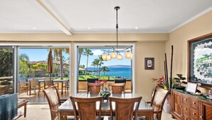 A dining area with a view of the ocean, a large window, and a ceiling light fixture. - Makena Surf G-201 - Corner Unit With Amazing Views, Pools, Pickleball & Peloton (Kihei)