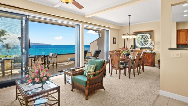 A spacious room with a view of the ocean, a dining area, and a ceiling fan. - Makena Surf G-201 - Corner Unit With Amazing Views, Pools, Pickleball & Peloton (Kihei)