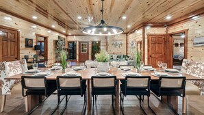 A wooden-paneled room with a large dining table set for six, surrounded by chairs. - Cabin in Sevierville Sleeps 28 Pool Hot Tub (Sevierville)