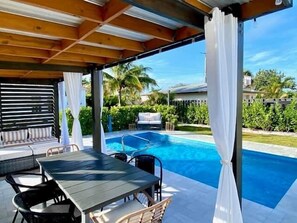 Un espacio al aire libre cubierto con piscina, una mesa con sillas y un sofá.