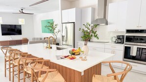 Una cocina moderna con una isla central, armarios blancos y un horno empotrado.