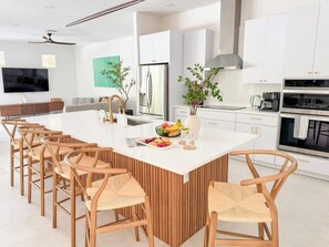 A modern kitchen with a central island, white cabinetry, and a built-in oven. - Naples FL | Heated Pool Spa Pickleball Mini Golf (Naples)