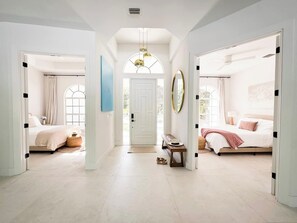 A bright, spacious hallway leading to two bedrooms with large windows, a central door, and a ceiling fan. - Naples FL | Heated Pool Spa Pickleball Mini Golf (Naples)
