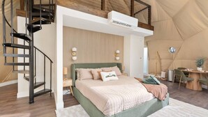 Un dormitorio con cama, escritorio y escalera de caracol.
