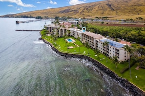 Ein Hotel an der Küste mit Schwimmbad, mehreren Gebäuden und Blick auf Meer und Hügel.