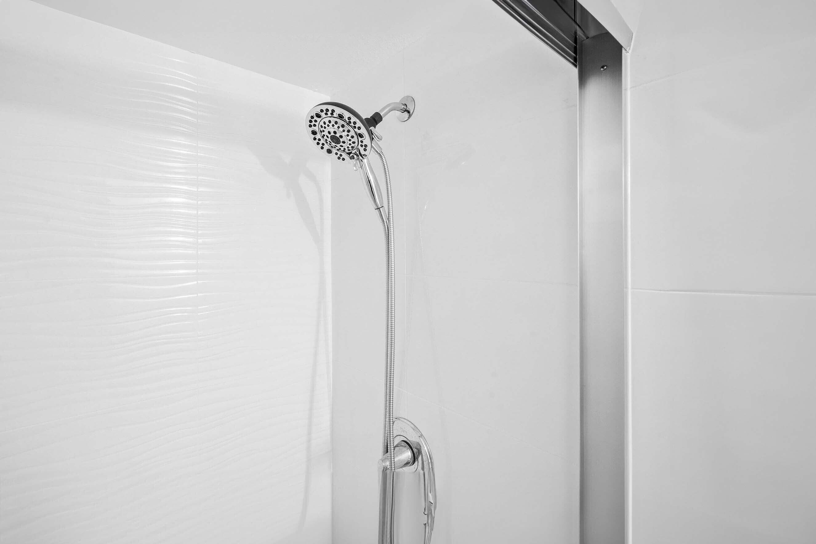 A modern shower with a handheld showerhead and a flexible hose.