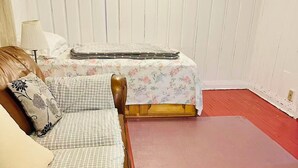 A room with a brown leather sofa, a checkered sofa, a bed with a floral bedspread, and a red floor. - Entire rental unit in Montreal, Canada (Montréal)