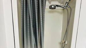 A small, enclosed shower area with a showerhead and hose, a white door, and a dark shower curtain. - Entire rental unit in Montreal, Canada (Montréal)