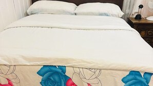 A bed with a white bedspread and a floral design, a wooden nightstand with a lamp, and a red floor. - Entire rental unit in Montreal, Canada (Montréal)