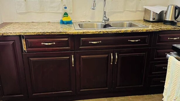 A kitchen with dark wooden cabinets, a granite countertop, a stainless steel sink, and a toaster. - Entire rental unit in Montreal, Canada (Montréal)