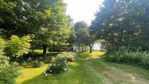Un sendero atraviesa un jardín exuberante con árboles y un edificio blanco a lo lejos.