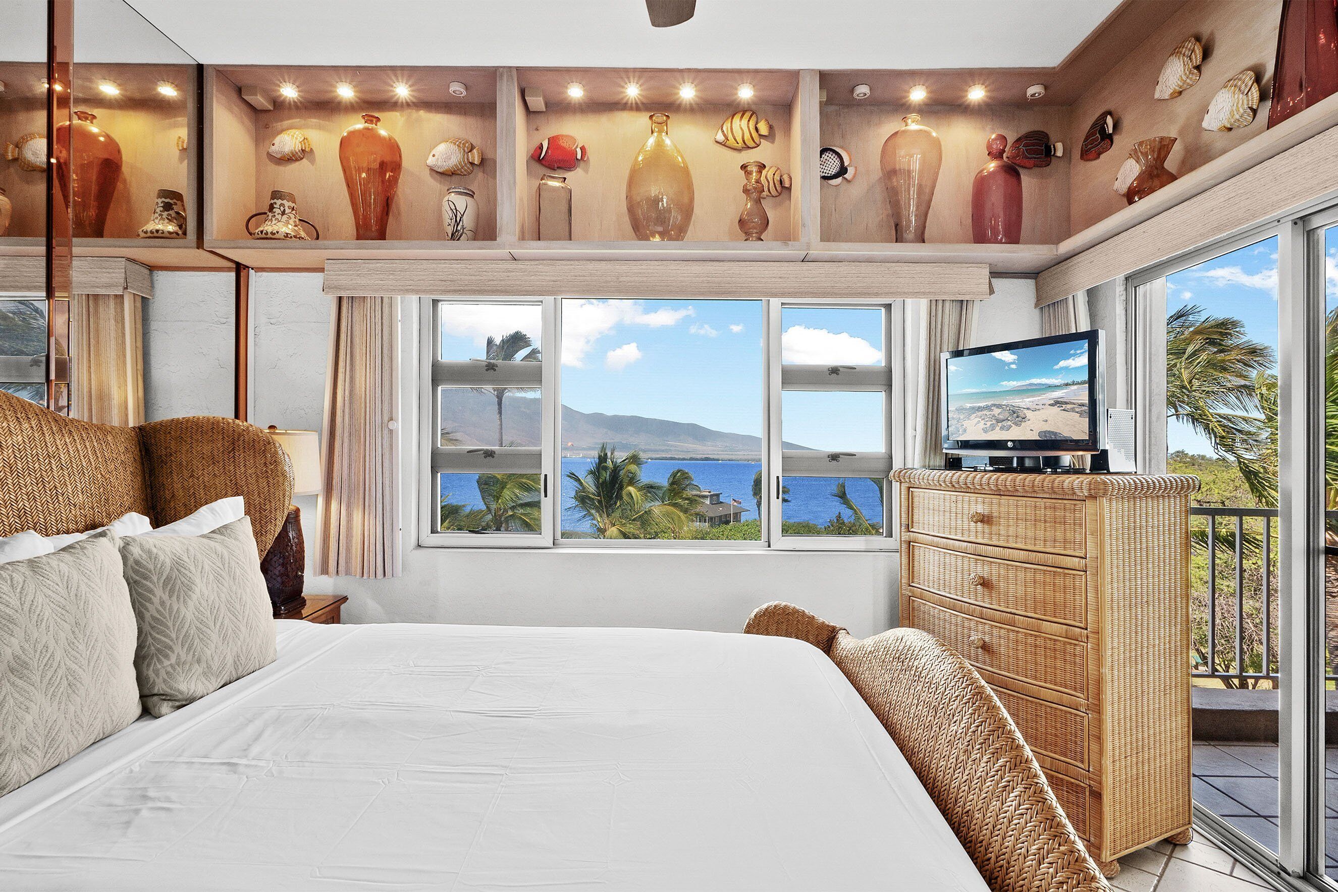 A bedroom with a large bed, a television, and a view of the ocean.