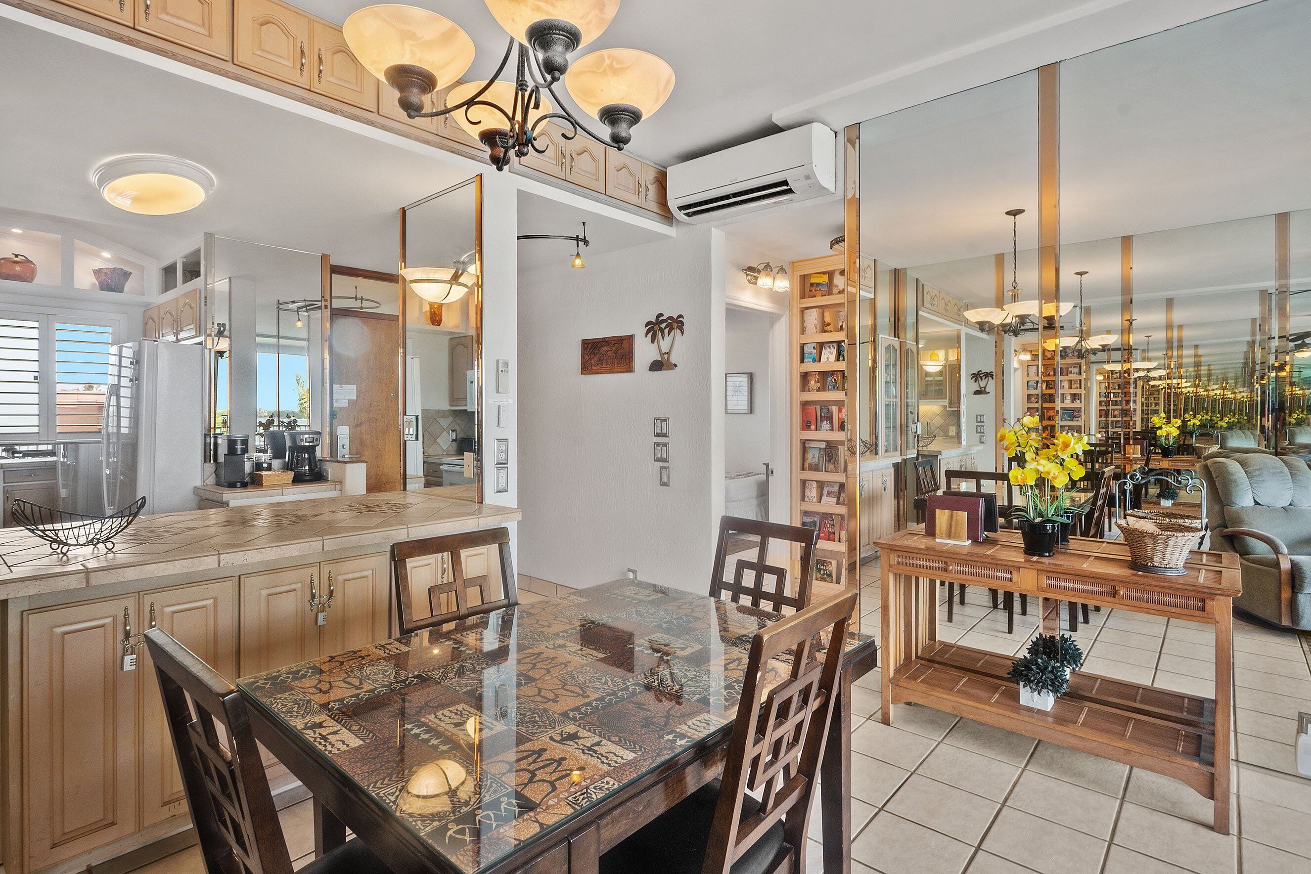 A spacious kitchen with a large island, wooden cabinets, and a dining area with a glass-top table and chairs.