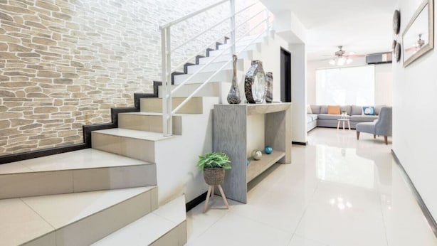 Ein modernes Interieur mit einer Steinwand, einer Treppe, einem grauen Sofa und einem kleinen Tisch.