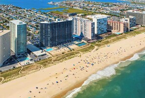 Ein Küstenhotelbereich mit mehreren Hochhäusern, einem Sandstrand und einem Poolbereich.