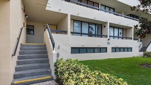 Un edificio moderno a due piani con una scalinata che conduce all'ingresso, un tetto piano e un prato ben curato.