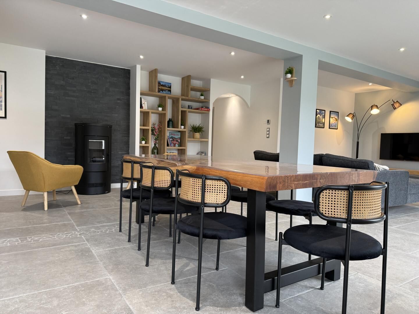 Een moderne eethoek met een houten tafel en zwarte stoelen, een bank en een open haard.