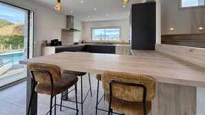 A modern kitchen with a large island, bar stools, and pendant lighting. - IBARNIA - SUHESCUN - Gîte (SUHESCUN)