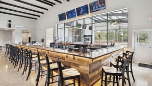 Zona de bar àmplia, amb una barra llarga, molts taburets i grans finestres que donen vistes a l'exterior.