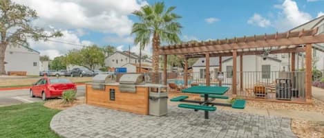 An outdoor patio area with a grill, picnic table, and covered seating area.