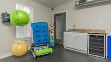 Una habitación con kitchenette, equipo de ejercicio y una puerta que conduce a otra habitación.
