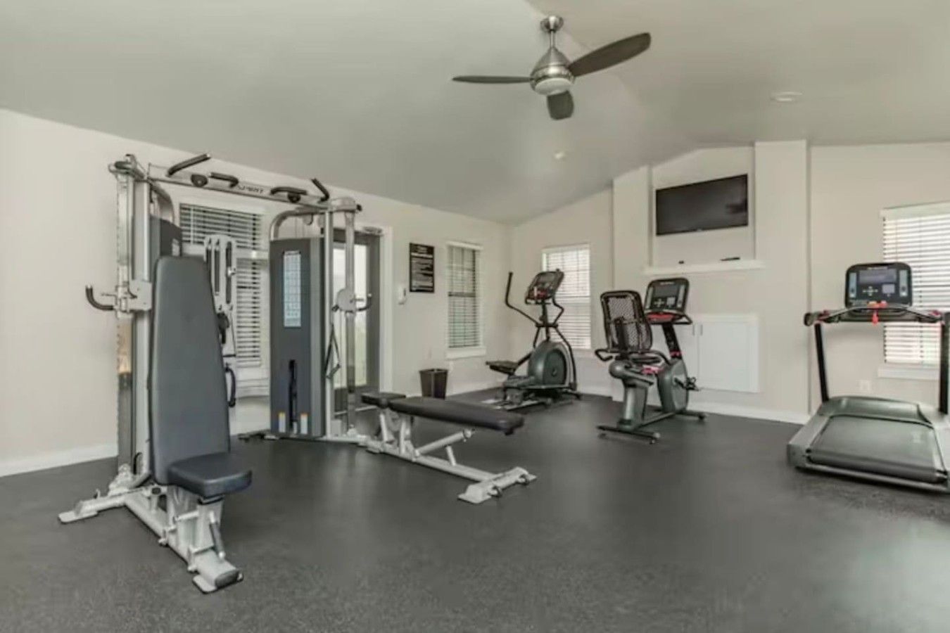 A gym with various exercise equipment including a treadmill, elliptical, and weight machines.