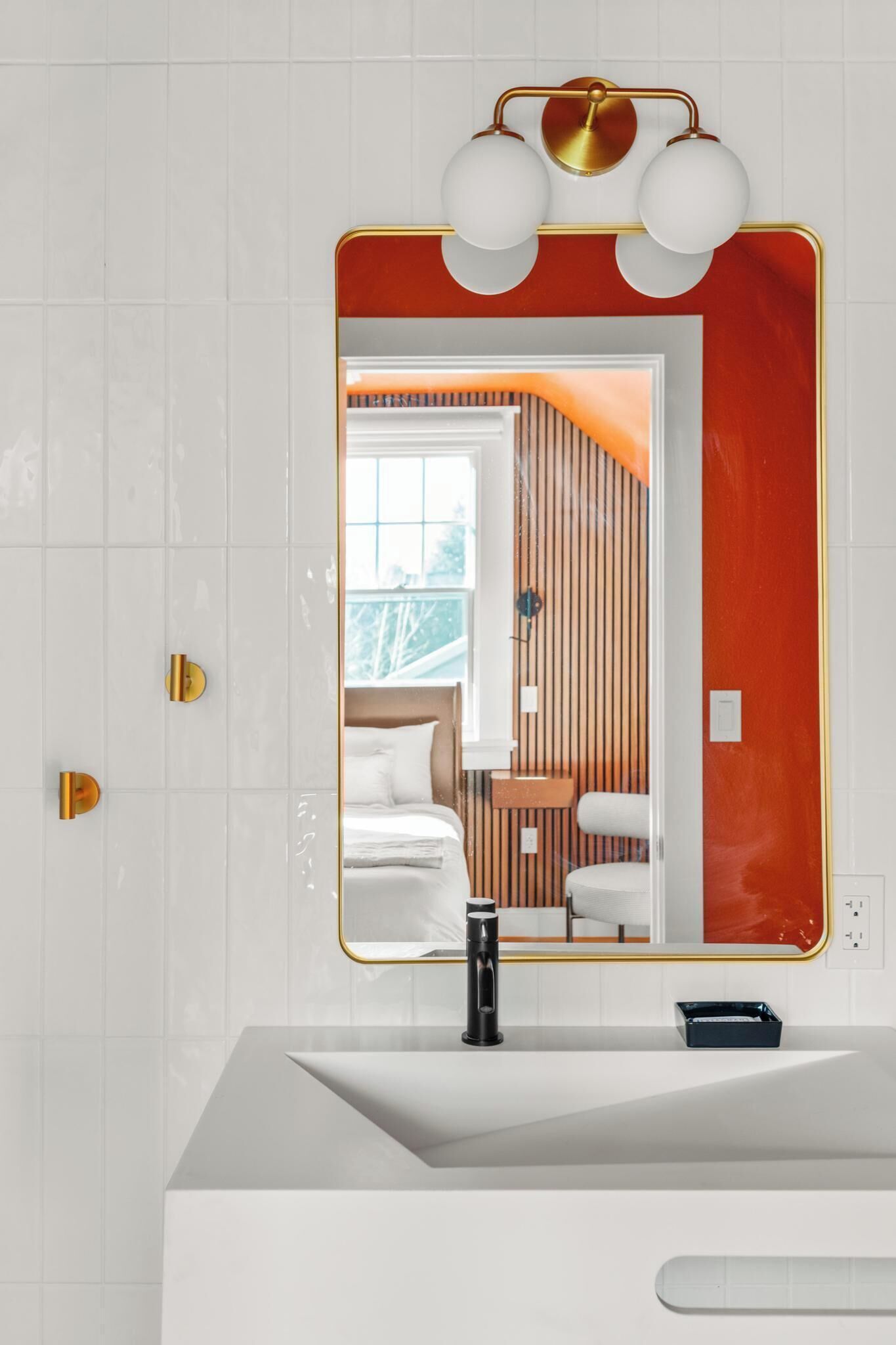 A modern bathroom with a white vanity, a large mirror, and a red accent wall.