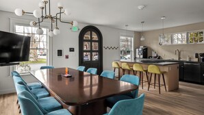 A modern kitchen with a large island, bar stools, and a dining area with a long table and chairs. - Assemble Boise (Boise)