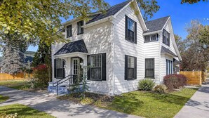 A two-story house with a front porch, a garage, and a well-maintained lawn. - Assemble Boise (Boise)