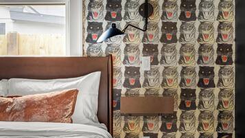 A bedroom with a bed, a nightstand, a lamp, and a wall with a tiger pattern.