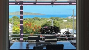 Un espace extérieur abrité, aménagé avec des sièges, et offrant une vue sur la mer et les collines.